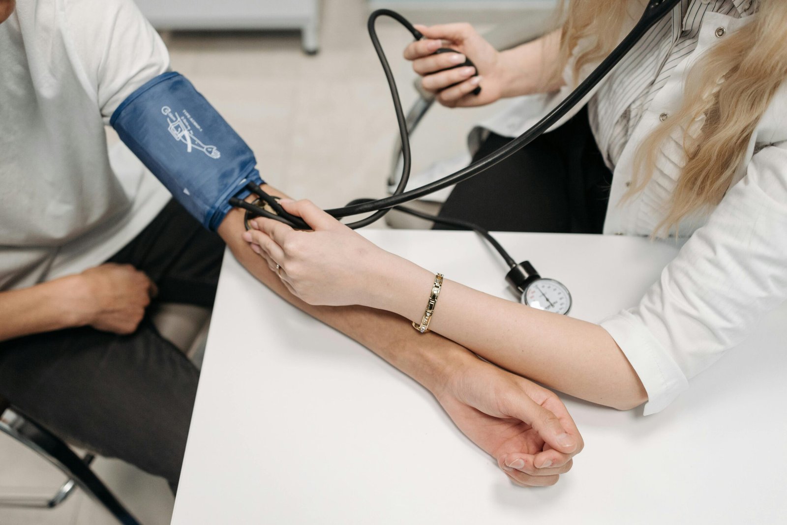 pexels-photo-7108344-7108344 A doctor measures a patient's blood pressure with a sphygmomanometer during a consultation.